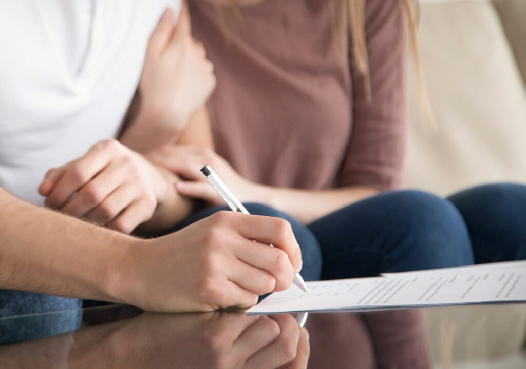 Young couple reviewing and signing buyer’s home inspection agreement
