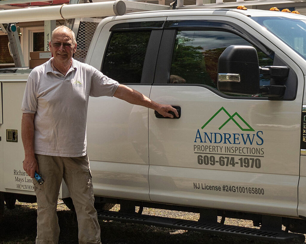 Inspector, Richard Andrews stands alongside company truck that reads 'Andrews Property Inspections 609-674-1970' on door.